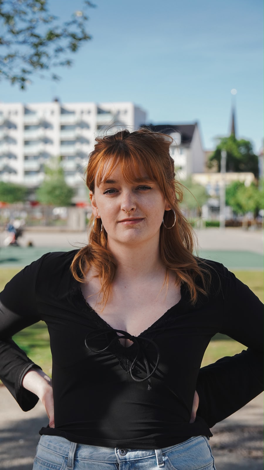 Simone Lux steht in einem Park und schaut entschlossen in die Kamera.