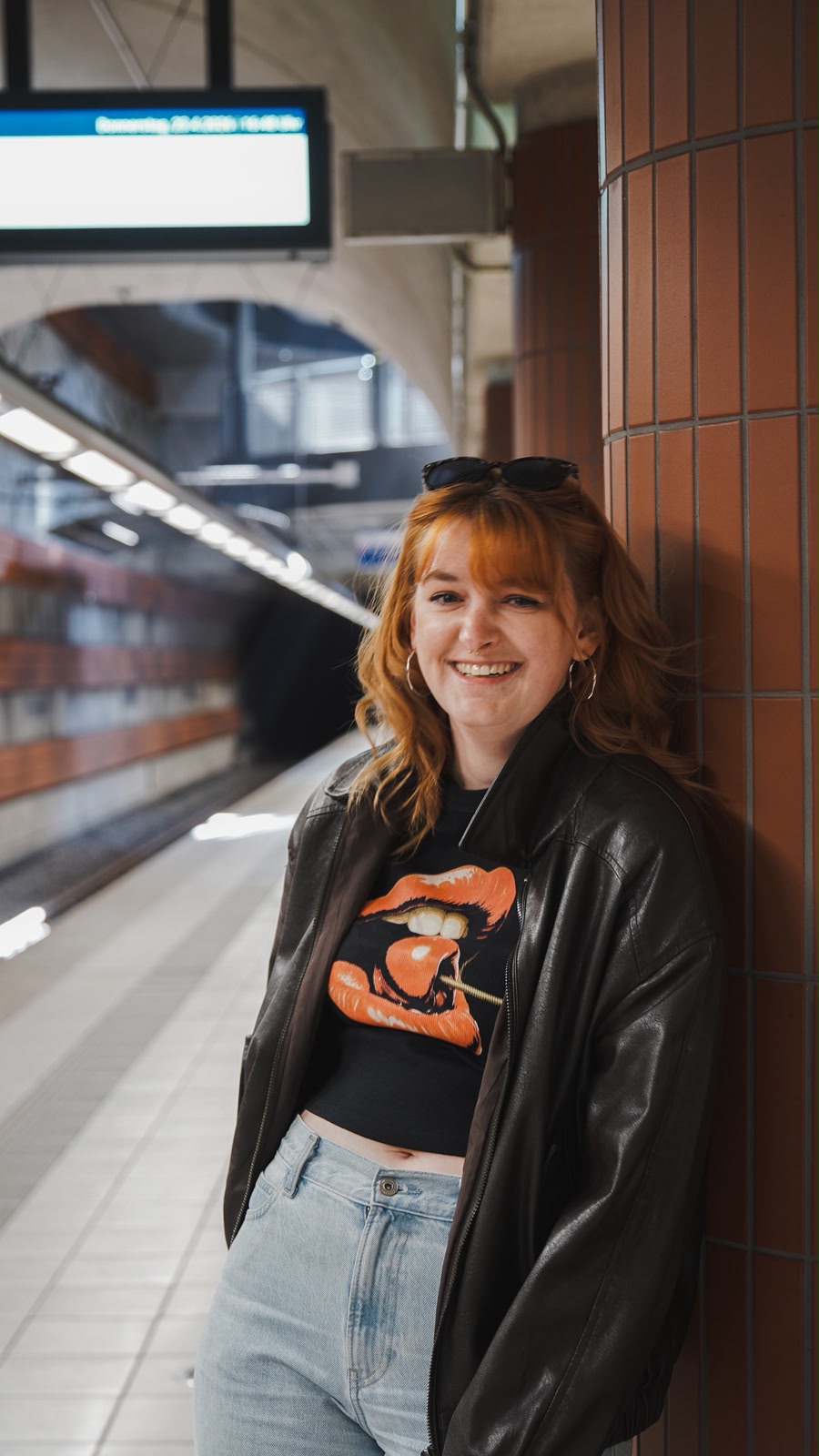 Simone Lux lehnt sich in einer U-Bahn-Haltestelle an eine Säule und lächelt in die Kamera.